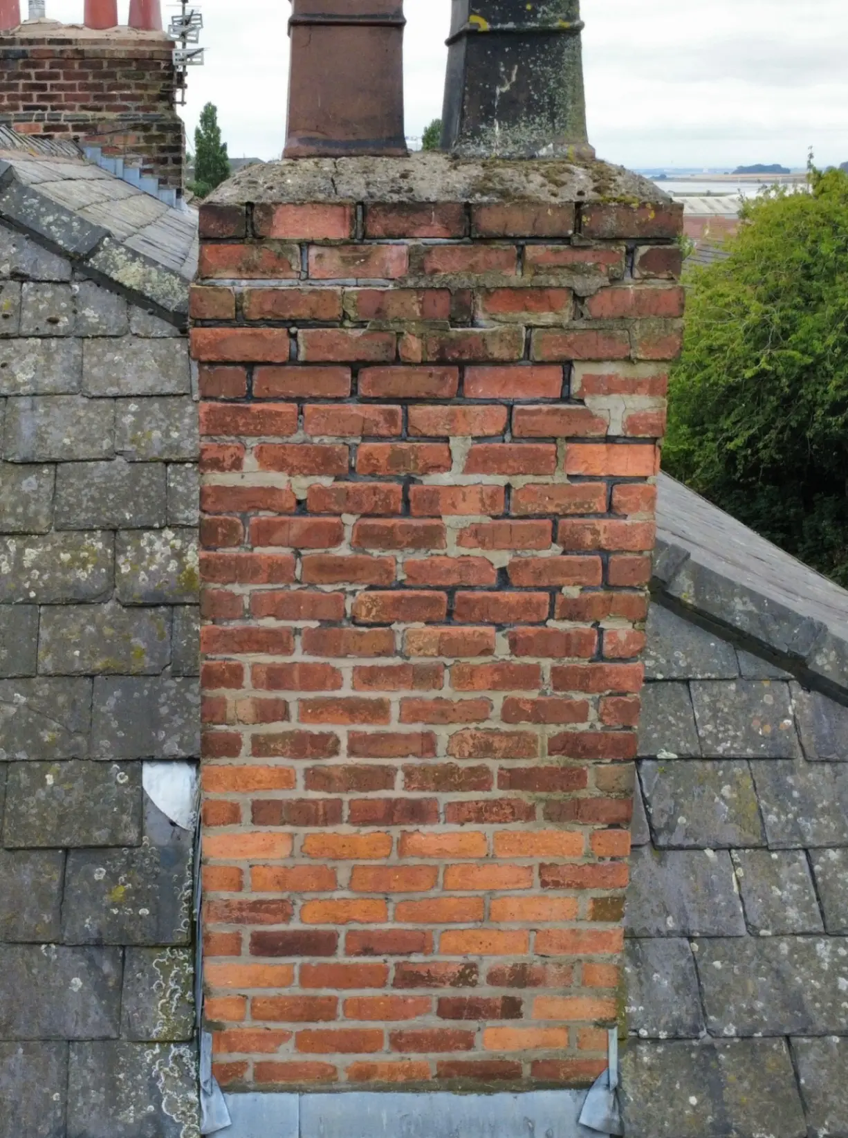 Before: The same chimney with eroded mortar joints before repointing