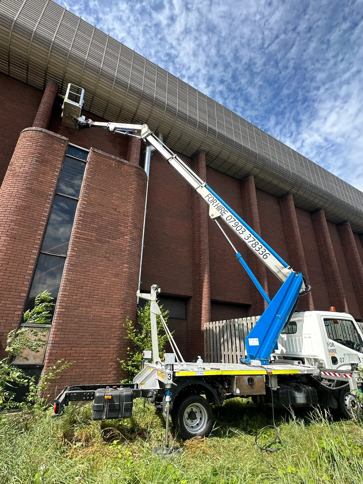 Operator in cherry picker basket working at height on a commercial building