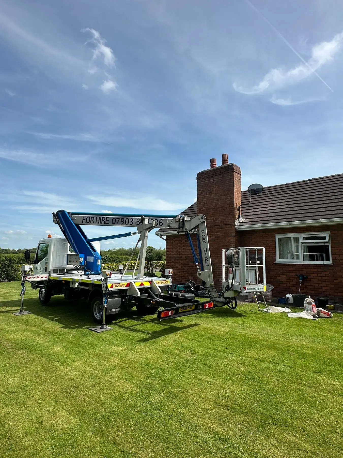 The Halton Cherry Pickers truck set up on outriggers at a bungalow, basket raised to the chimney